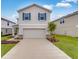 Two-story house with beige siding, two-car garage, and landscaping at 424 Wayland Dr, Haines City, FL 33844