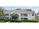 Exterior view of the property featuring white facade, grey roof, well-manicured lawn and mature trees at 570 Cranes Way # 248, Altamonte Springs, FL 32701