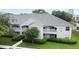 Exterior view of the property featuring white facade, grey roof, well-manicured lawn and mature trees at 570 Cranes Way # 248, Altamonte Springs, FL 32701