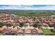 This aerial view of the neighborhood shows the houses with red roofs with lush greenery and bodies of water at 3047 Sangria St, Kissimmee, FL 34744