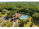 Aerial view of clubhouse, pool, and tennis court amenities enveloped by a verdant landscape, offering a serene community experience at 3047 Sangria St, Kissimmee, FL 34744