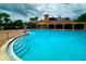 Community pool with steps leading into the blue water and a building in the background surrounded by palm trees at 3047 Sangria St, Kissimmee, FL 34744