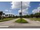 Well-maintained community street with manicured landscaping, palm trees, and clear signage under a bright blue sky at 3047 Sangria St, Kissimmee, FL 34744