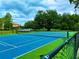 Well-maintained tennis court with vibrant blue and green surface surrounded by lush greenery and a clear blue sky at 3047 Sangria St, Kissimmee, FL 34744