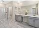 Bathroom featuring double sink vanity, walk-in shower with glass door, and marble-look tiling at 8938 Cabot Cliffs Dr, Davenport, FL 33896