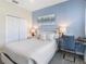 Comfortable bedroom with blue accent wall, white bedding, and a convenient desk workspace at 8938 Cabot Cliffs Dr, Davenport, FL 33896
