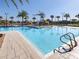 Community pool with palm trees, cabanas, lounge chairs and manicured landscaping at 8938 Cabot Cliffs Dr, Davenport, FL 33896