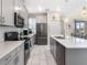 Bright, neutral kitchen featuring stainless appliances, a large island, and sleek white backsplash at 8938 Cabot Cliffs Dr, Davenport, FL 33896