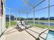 Covered patio with three lounge chairs overlooks pond and neighboring houses under clear blue skies at 8938 Cabot Cliffs Dr, Davenport, FL 33896