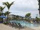 Community swimming pool with lounge chairs and palm trees on a partly cloudy day at 8938 Cabot Cliffs Dr, Davenport, FL 33896