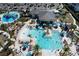 Aerial view of a resort style pool with lounge chairs, palm trees, umbrellas and a splash pad at 8938 Cabot Cliffs Dr, Davenport, FL 33896