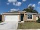 Tan one-story house with white garage door and teal front door, new landscaping at 5457 Hayloft Dr, Apopka, FL 32712