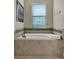 Elegant soaking tub with tiled surround and window view at 8930 Azalea Sands Ln, Davenport, FL 33896