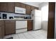 Galley kitchen with brown cabinets, white appliances, and neutral tile flooring, perfect for easy upkeep at 3276 Candle Ridge Ct # 202, Orlando, FL 32822
