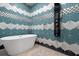 A modern bathroom features a geometric tiled wall, soaking tub, and a sleek, multi-jet shower panel at 1021 Fantasy Dr, Davenport, FL 33896