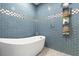 Modern bathroom features a soaking tub, a rain shower, and unique blue subway tile at 1021 Fantasy Dr, Davenport, FL 33896