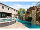 Backyard swimming pool featuring a rock waterfall, hot tub, and lounge chairs for relaxation at 1021 Fantasy Dr, Davenport, FL 33896