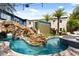 Outdoor pool area featuring rock waterfall, lush landscaping, and large outdoor screen at 1021 Fantasy Dr, Davenport, FL 33896