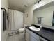 Well-lit bathroom features a shower-tub combo, a sleek vanity with a black countertop, and neutral tile floor at 2346 Upland Ln, Apopka, FL 32712