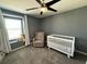 Cozy Bedroom with a white crib, comfortable chair, ceiling fan, and a teddy bear by the window at 2346 Upland Ln, Apopka, FL 32712