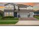 Two-story home with a three-car garage, brick paver driveway, manicured lawn and gray siding at 3198 Sailing Pier Ave, Winter Garden, FL 34787