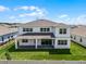 Rear exterior featuring a covered patio, ample windows and a well-manicured lawn under a sunny sky at 3198 Sailing Pier Ave, Winter Garden, FL 34787