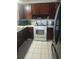 Cozy kitchen featuring wood cabinets, white appliances, and tile flooring at 108 5Th Jpv St, Winter Haven, FL 33880