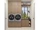 Well-organized laundry room with full-sized washer and dryer, shaker cabinetry, and a view to the outdoors at 110 W Railway Ave, Oakland, FL 34760