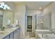 Bathroom featuring double vanity with granite countertop, walk-in shower, and view into walk-in closet at 1687 Kona Ln, Davenport, FL 33897