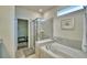 Bright bathroom featuring a tiled glass shower, soaking tub, and a view into the walk-in closet at 1687 Kona Ln, Davenport, FL 33897