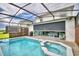 A screened-in pool and hot tub with an automatic shade over the outdoor kitchen and seating area at 1687 Kona Ln, Davenport, FL 33897