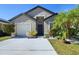 Tan house with dark brown trim, white garage door, and landscaped front yard at 13136 S Ashington Pointe Dr, Orlando, FL 32824