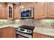Stainless steel microwave and oven in kitchen with wooden cabinets and tile backsplash at 1730 Stafford Springs Blvd, Mount Dora, FL 32757