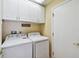 Bright laundry room with overhead cabinets and full-size washer and dryer for convenience at 1730 Stafford Springs Blvd, Mount Dora, FL 32757
