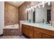 Elegant bathroom featuring dual vessel sinks, a soaking tub, and tiled walls at 349 La Creek Ct, Debary, FL 32713