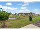 Backyard showcases a pond view, lush greenery, and community charm under a blue sky at 203 River Front Way, Edgewater, FL 32141