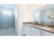 A bright bathroom featuring double sinks, granite countertops, and a glass-enclosed shower at 7554 Marker Ave, Kissimmee, FL 34747