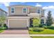 Two-story house with tan siding, two-car garage, and landscaping at 1116 Hendon Loop, Davenport, FL 33837