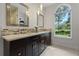 Elegant bathroom featuring double sinks, a decorative backsplash, and a large arched window with a garden view at 17577 Davenport Rd, Winter Garden, FL 34787