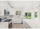 Close-up of the contemporary kitchen, featuring white cabinets and stainless steel appliances, with a clear view to the outdoors at 634 Burch Ave, Winter Garden, FL 34787