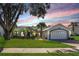 Charming single-story home featuring a well-manicured lawn, lush landscaping, and an attached two-car garage, all under a beautiful sky at 14310 Lord Barclay Dr, Orlando, FL 32837