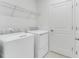 A clean laundry room with a washer, dryer, metal shelf, and a white door at 345 River Front Way, Edgewater, FL 32141