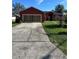 Charming red single-story home featuring a two-car garage and a well-manicured lawn at 305 Erie Ct, Kissimmee, FL 34759