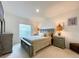 A well-lit bedroom with neutral tones featuring a comfortable bed, dresser, and a mounted TV at 1393 Asher Mason Ave, Kissimmee, FL 34744