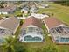 A closer aerial shot of three pool homes highlighting their screened enclosures and backyard layouts in a lush neighborhood at 246 Kimberly Point Dr, Davenport, FL 33837