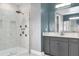 Modern bathroom features a glass enclosed shower, granite countertops, and gray cabinets at 13016 Shady Retreat Loop, Clermont, FL 34711