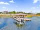 Daytime view of a wooden dock extending over the serene lake, complete with boat lift and covered sitting area at 13016 Shady Retreat Loop, Clermont, FL 34711