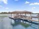 Daytime view of a wooden dock and boat lift extending over the serene lake, complete with covered sitting area at 13016 Shady Retreat Loop, Clermont, FL 34711