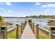 Daytime view of a wooden dock extending over the serene lake, complete with boat lift and covered sitting area at 13016 Shady Retreat Loop, Clermont, FL 34711