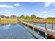 Daytime view of a wooden dock extending over the serene lake, offering serene lake views and neighborhood ambiance at 13016 Shady Retreat Loop, Clermont, FL 34711